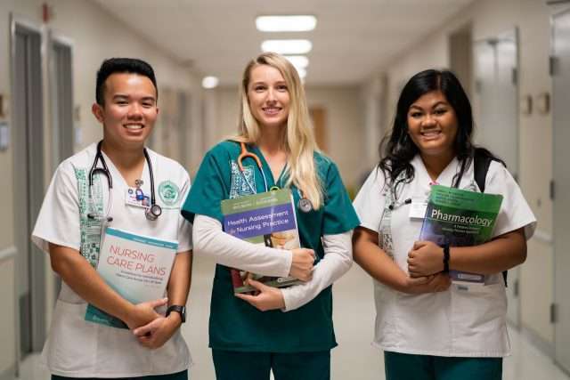 medical billing students posing with armful of books