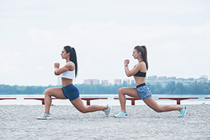 Two fit woman doing hip stretches.